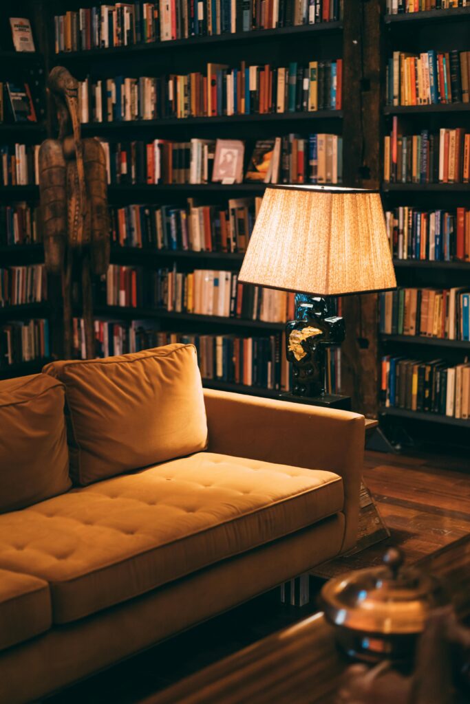 Warm and inviting library scene featuring a cozy couch, bookshelves, and a lamp for ambient lighting.